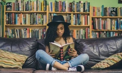 ungdom leser bok i sofa 