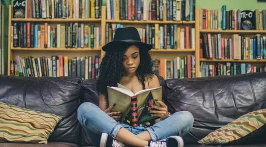 ungdom leser bok i sofa 